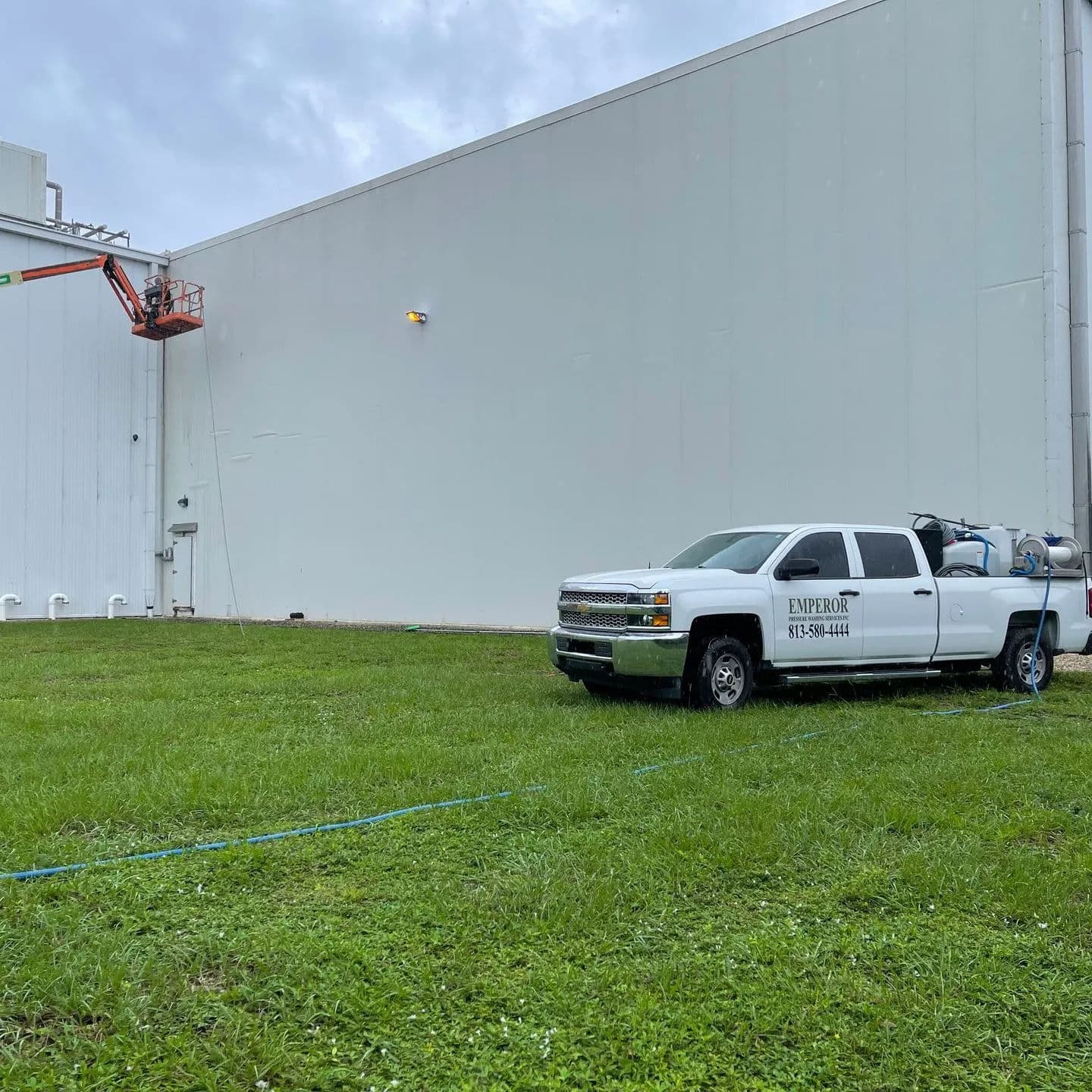 Pickup truck parked on grass near a building with maintenance crew using a lift.